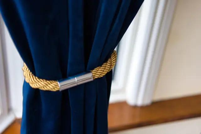 Navy velvet curtain held back with a gold rope tie