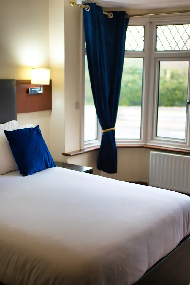 Double room with navy cushions on the bed and navy curtains at a leaded bay window