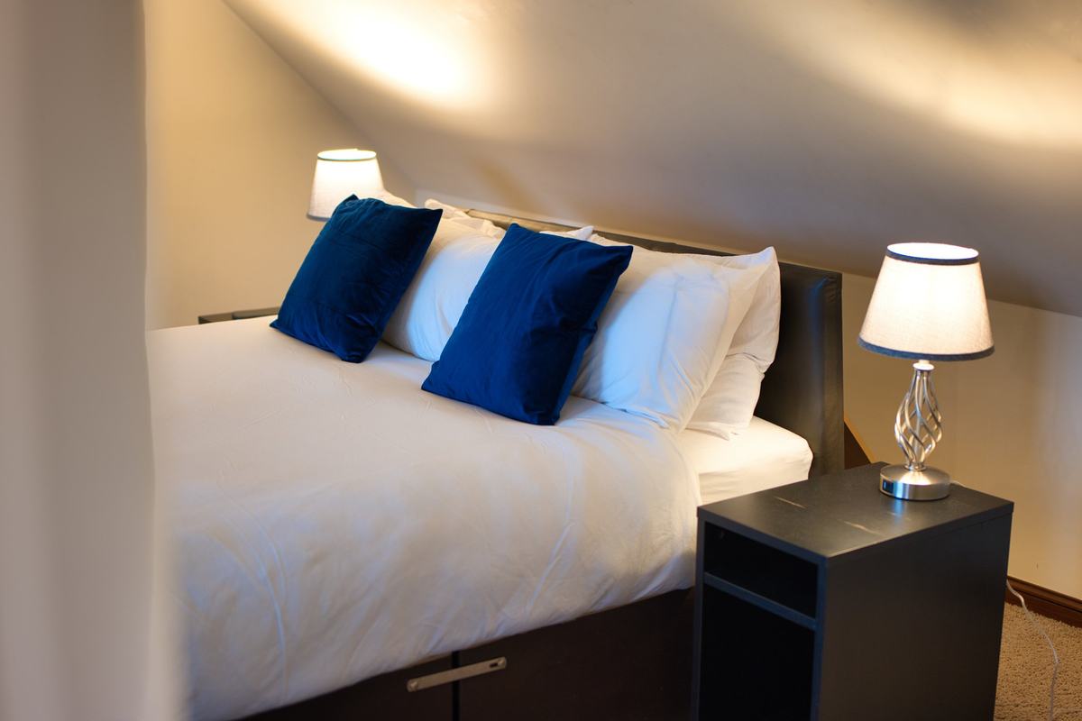 King-size bed in the Royal Clifton Suite with a crystal bedside lamp under the sloping top-floor ceiling