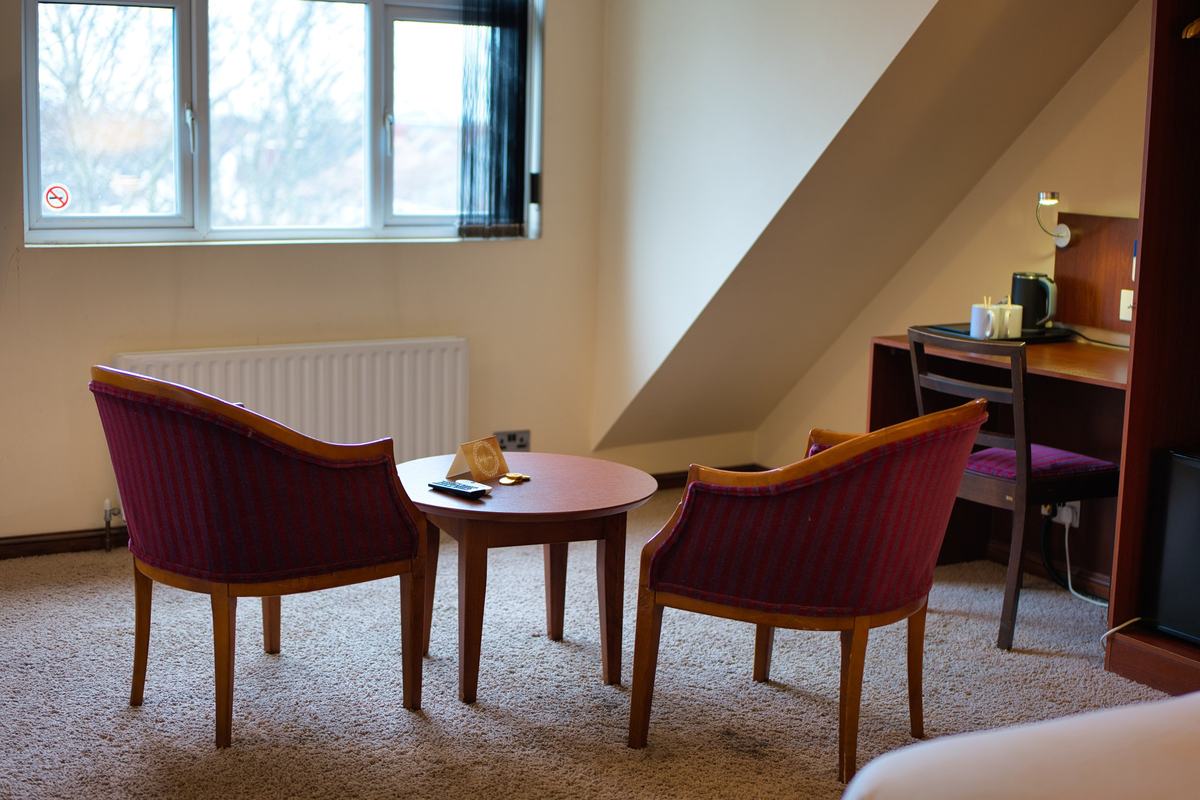 Seating area in the Royal Clifton Suite with two plum velvet armchairs and a round table by the window